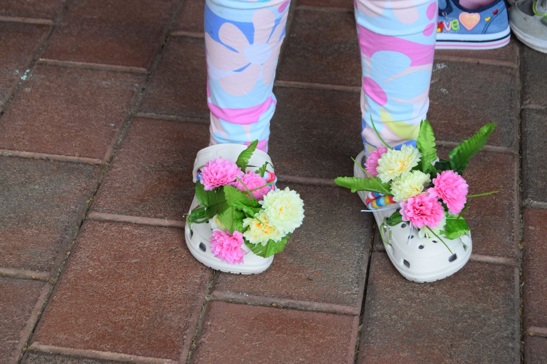A child wearing crocs with flowers on them