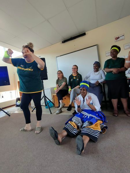 A woman in a green columbia shirt is dancing in front of a group of people
