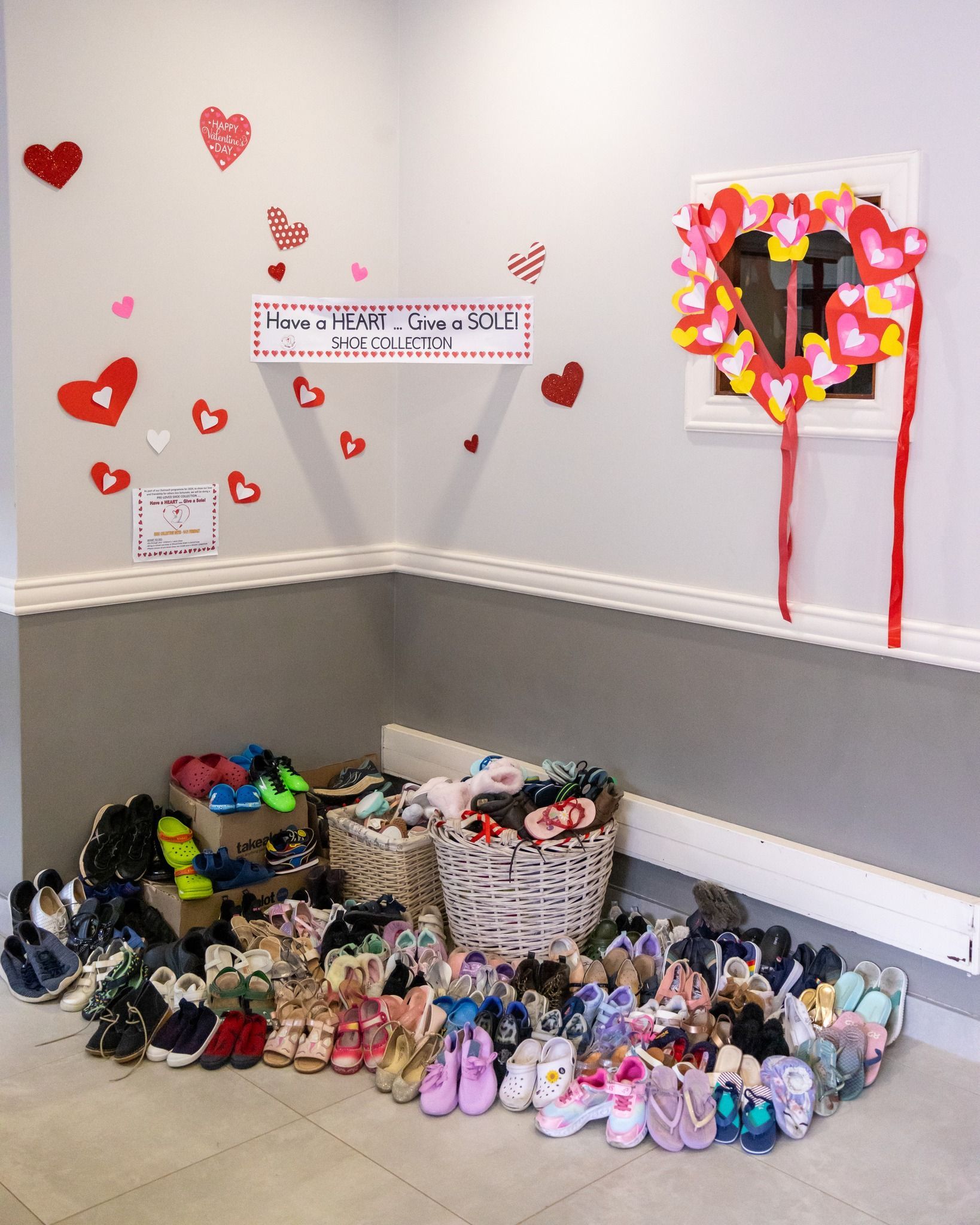 A bunch of shoes are on the floor in a room with hearts on the wall