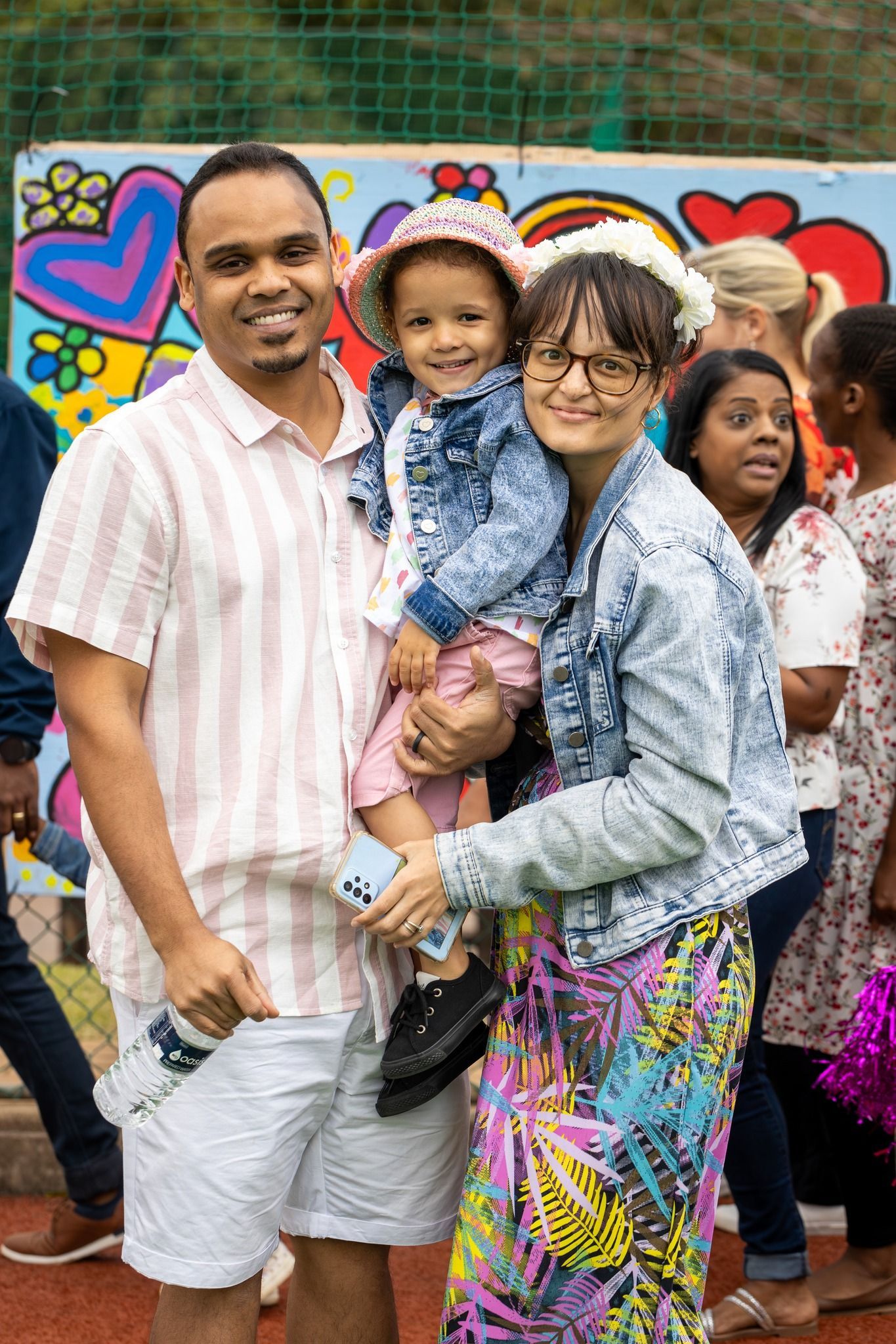 A man and woman are holding a little girl in their arms.