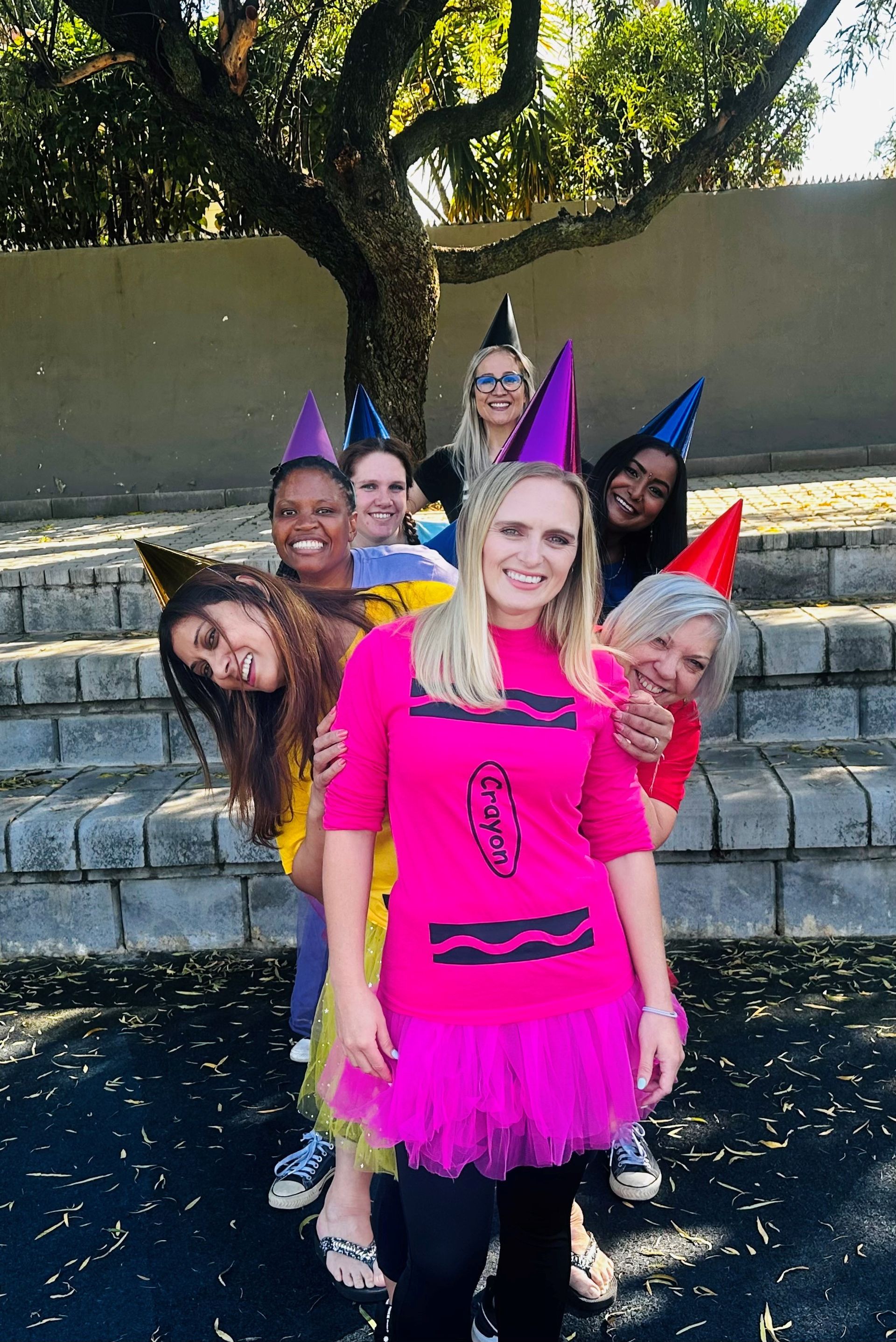 A group of people wearing party hats are posing for a picture.