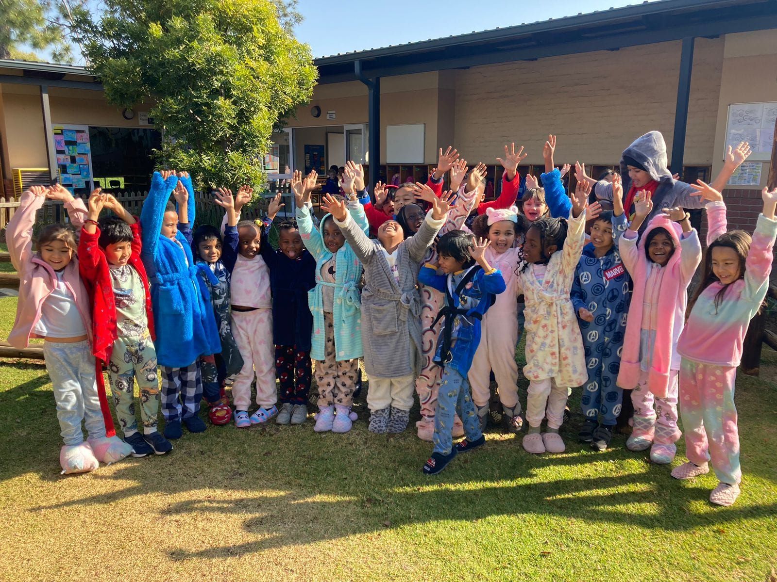 A group of children in pajamas are standing in front of a building.