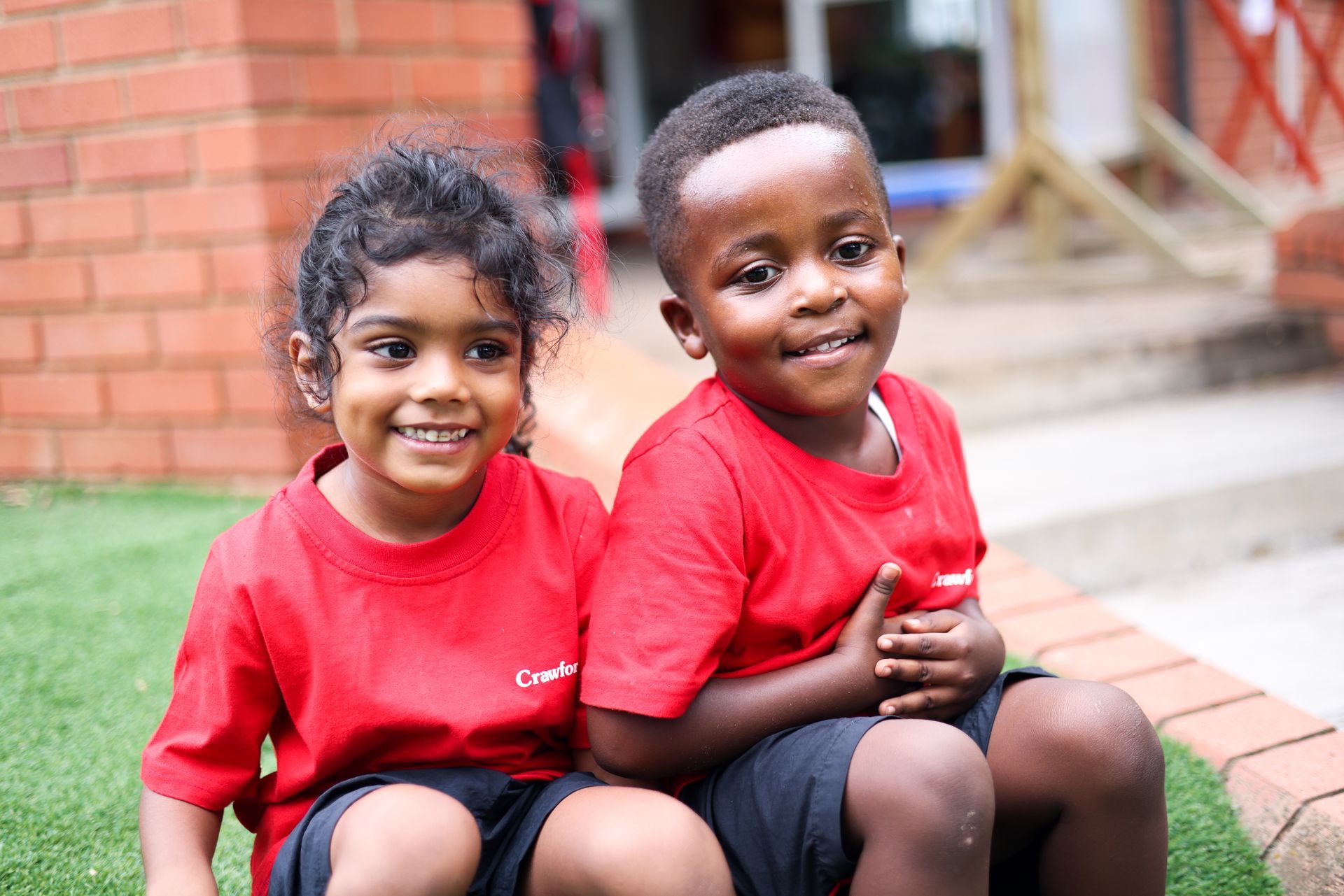 A boy and a girl are sitting next to each other on the grass.