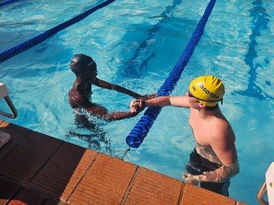 Two boys are holding hands in a swimming pool.