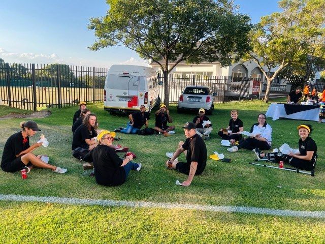 A group of people are sitting on the grass in a circle.