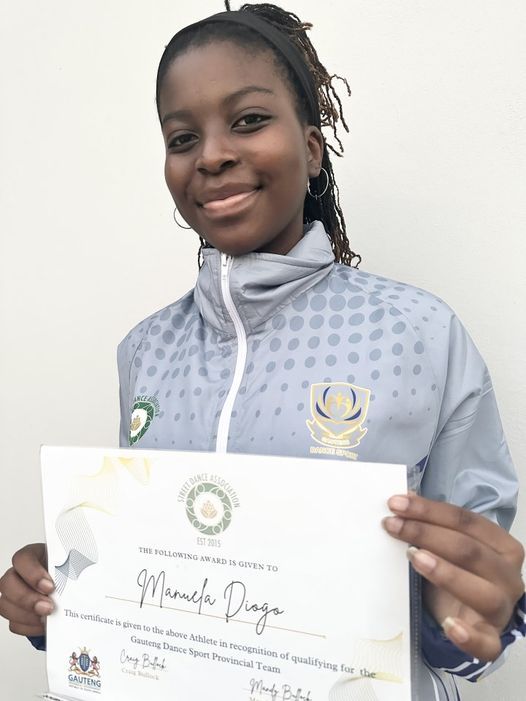A woman in a gray jacket is holding a certificate