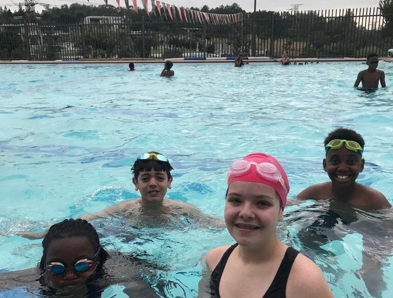 A group of children are swimming in a swimming pool.