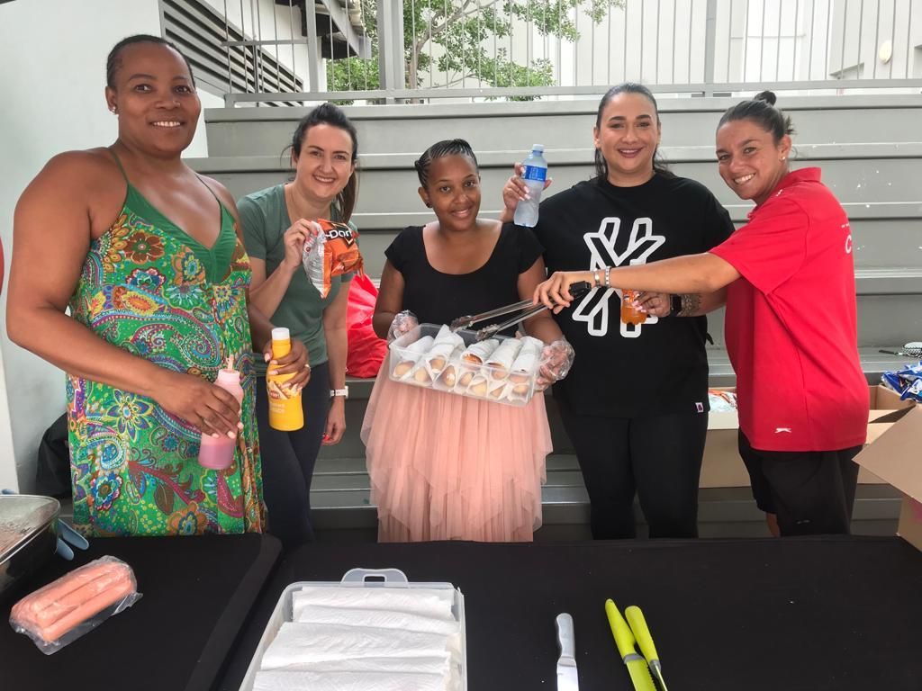 A group of women are standing around a table.