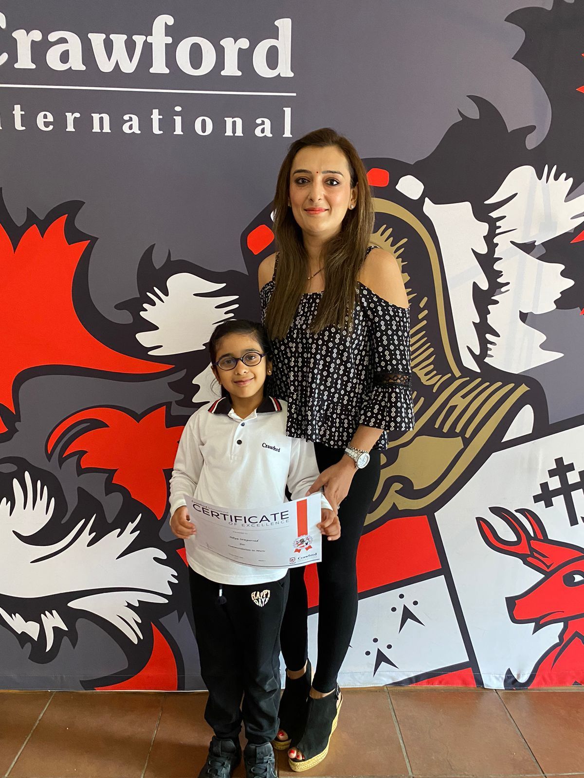 A woman and a little girl are standing in front of a crawford international sign.