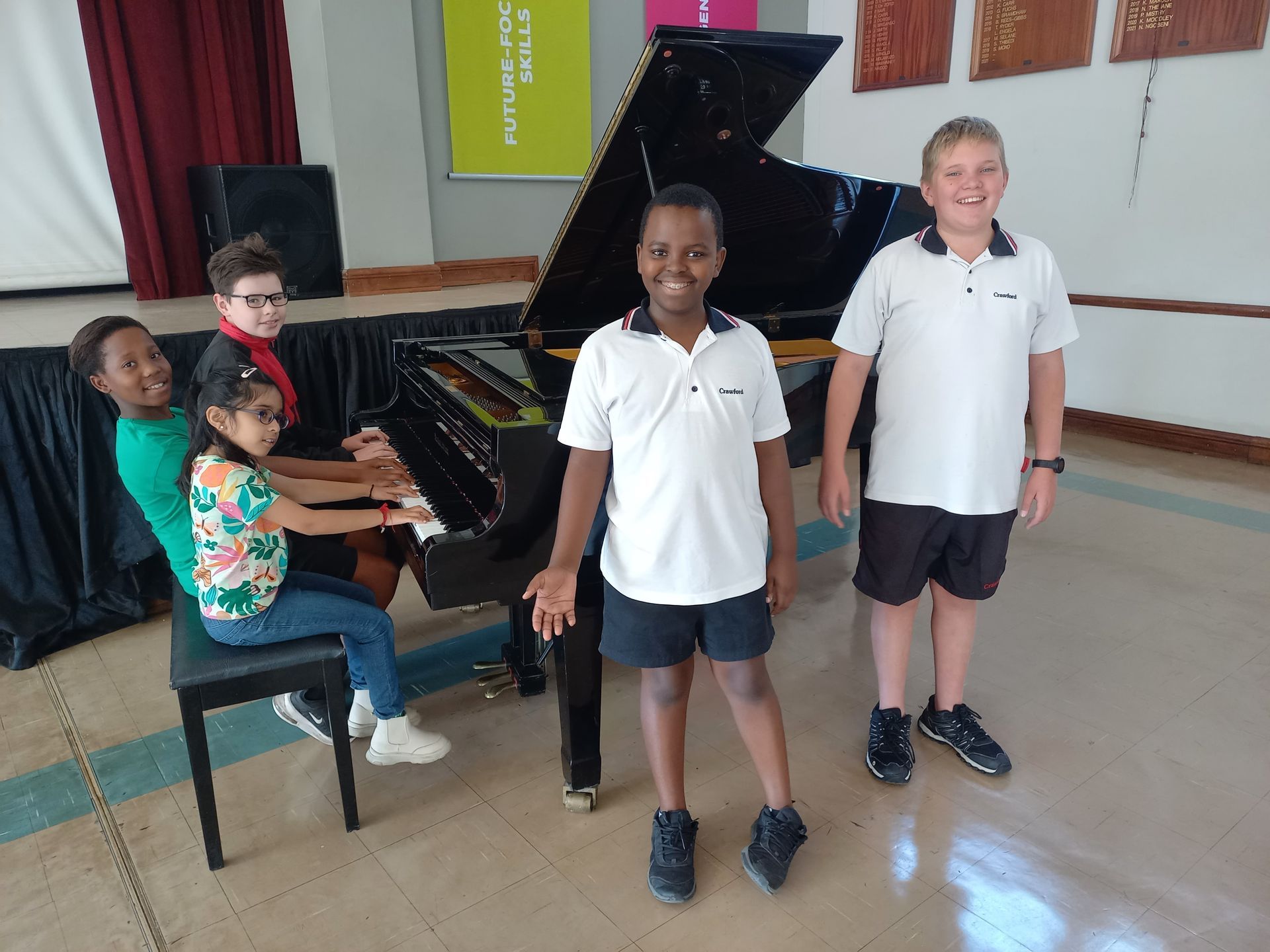 A group of children are standing in front of a piano.