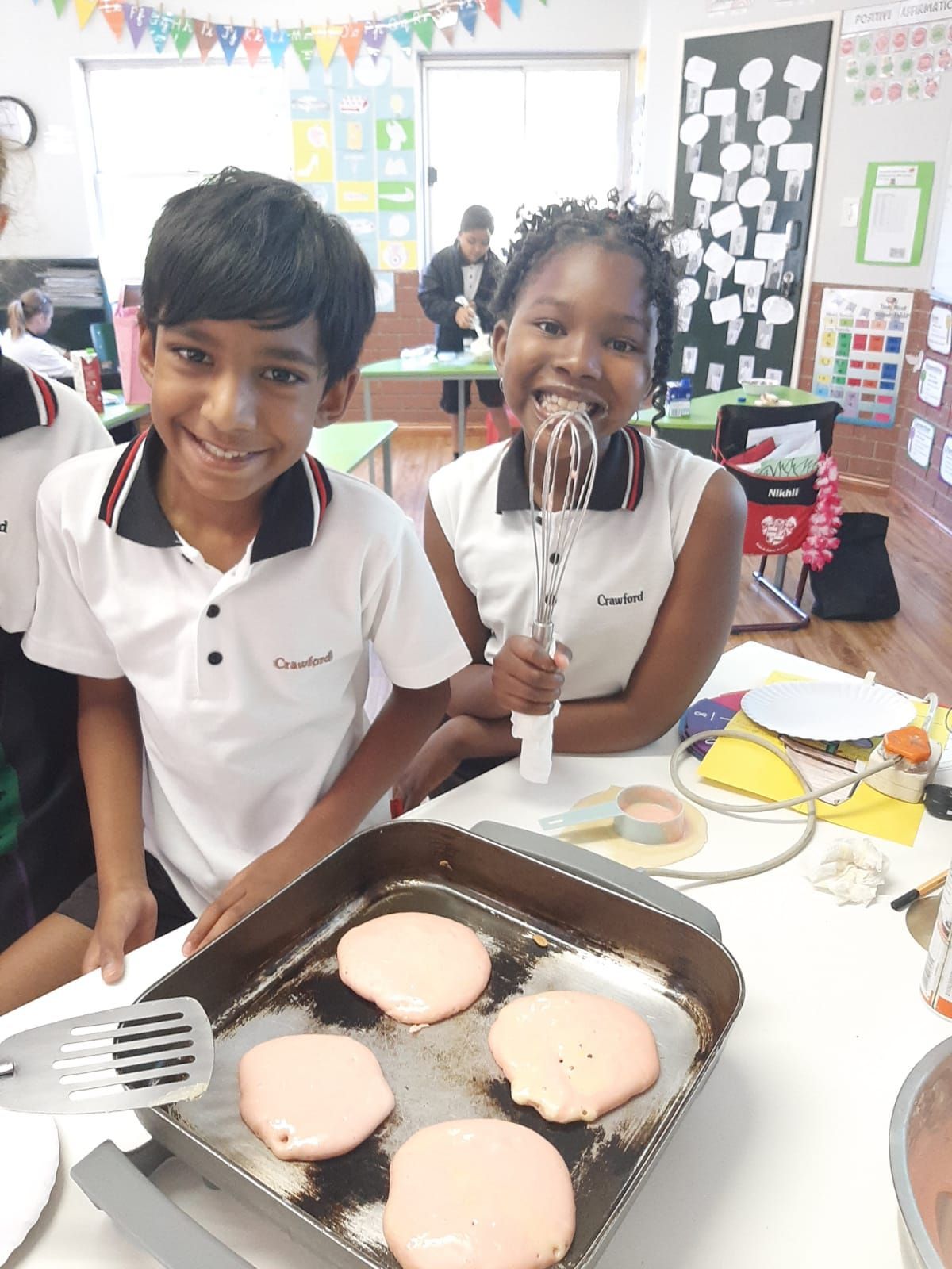 A boy and a girl are making pancakes in a classroom.