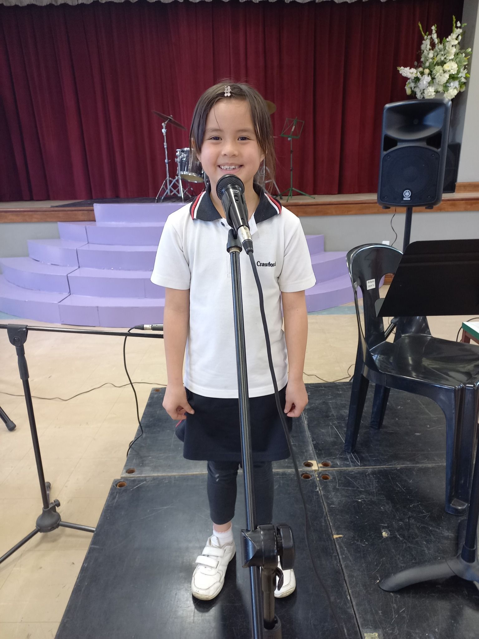 A little girl is standing in front of a microphone