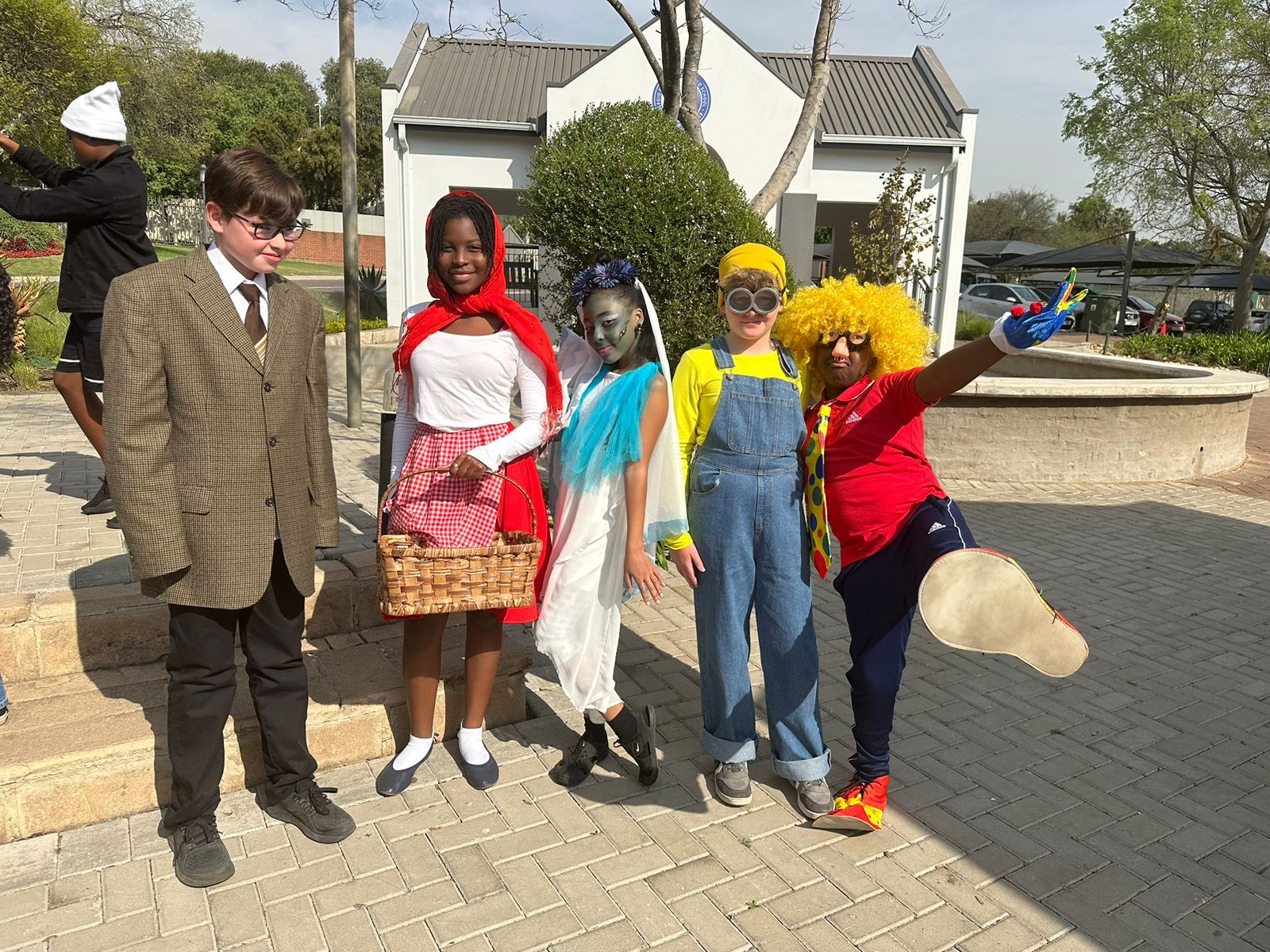 A group of children dressed in costumes are standing next to each other on a brick sidewalk.
