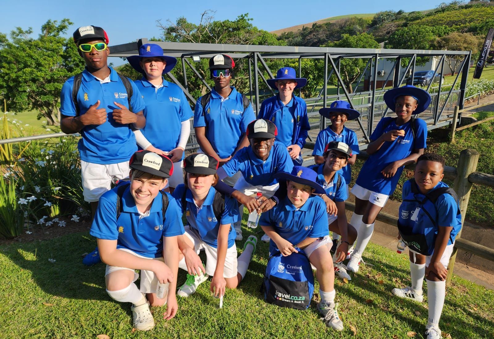 A group of young boys wearing blue shirts and hats are posing for a picture.