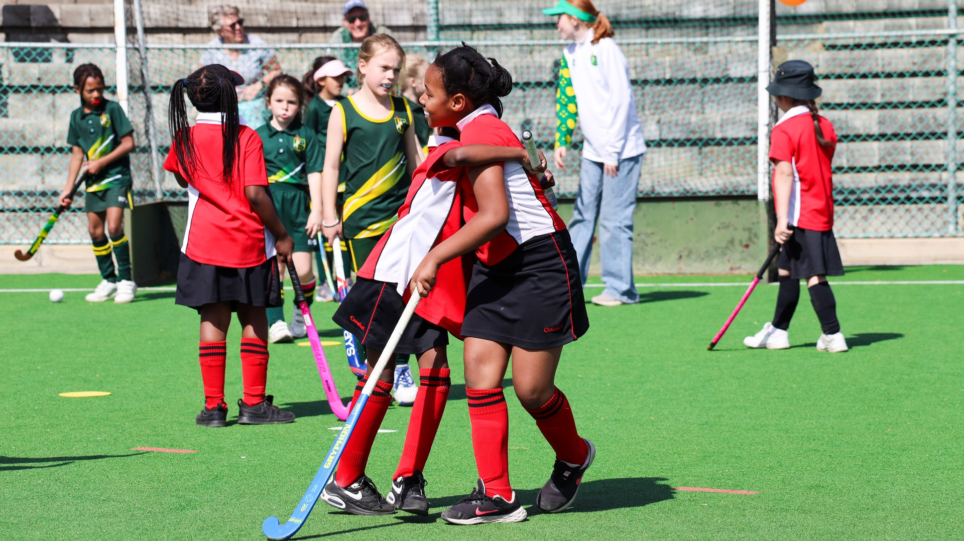 A group of young girls are playing field hockey on a field.