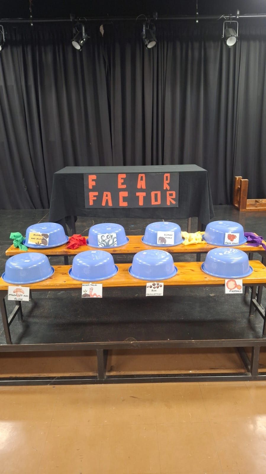A table with blue bowls on it and a sign that says `` fear factor ''.