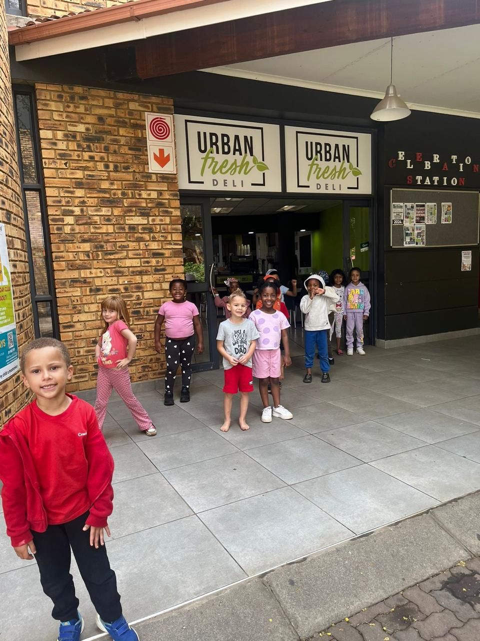 A group of children are standing in front of a building that says urban fresh