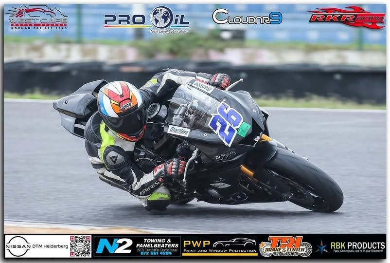 Motorcycle racer on a black bike with number 26 leans into a turn on a racetrack.
