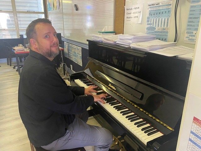 A man is playing a piano in a room.