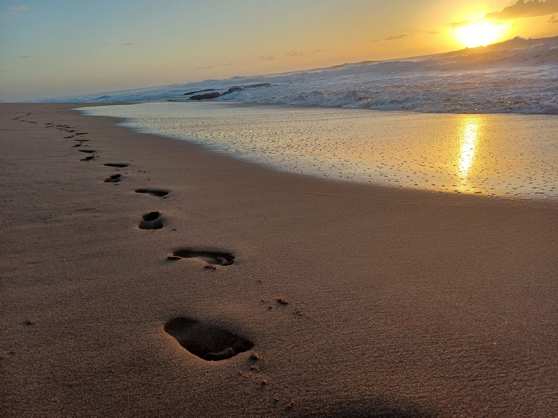 Footprints in the sand on a beach at sunset
