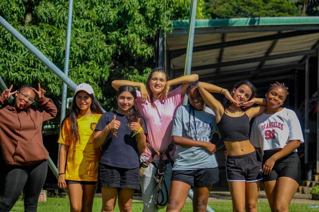 A group of young women are posing for a picture in a park.