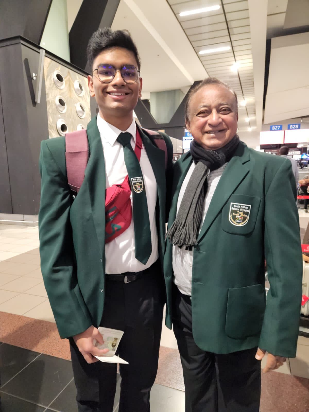 Two men are posing for a picture in an airport