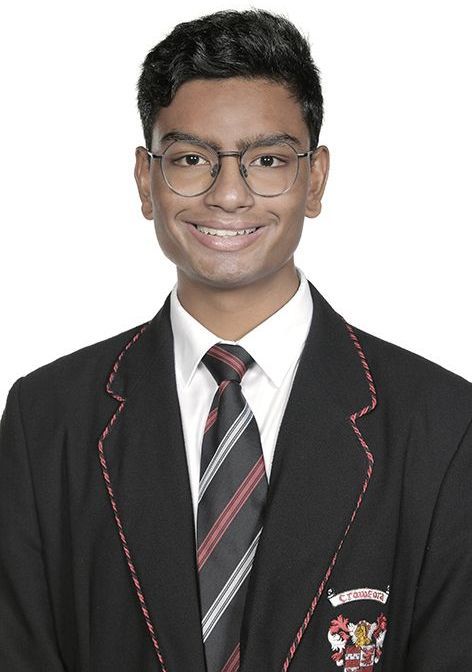 A young man in a suit and tie is smiling for the camera