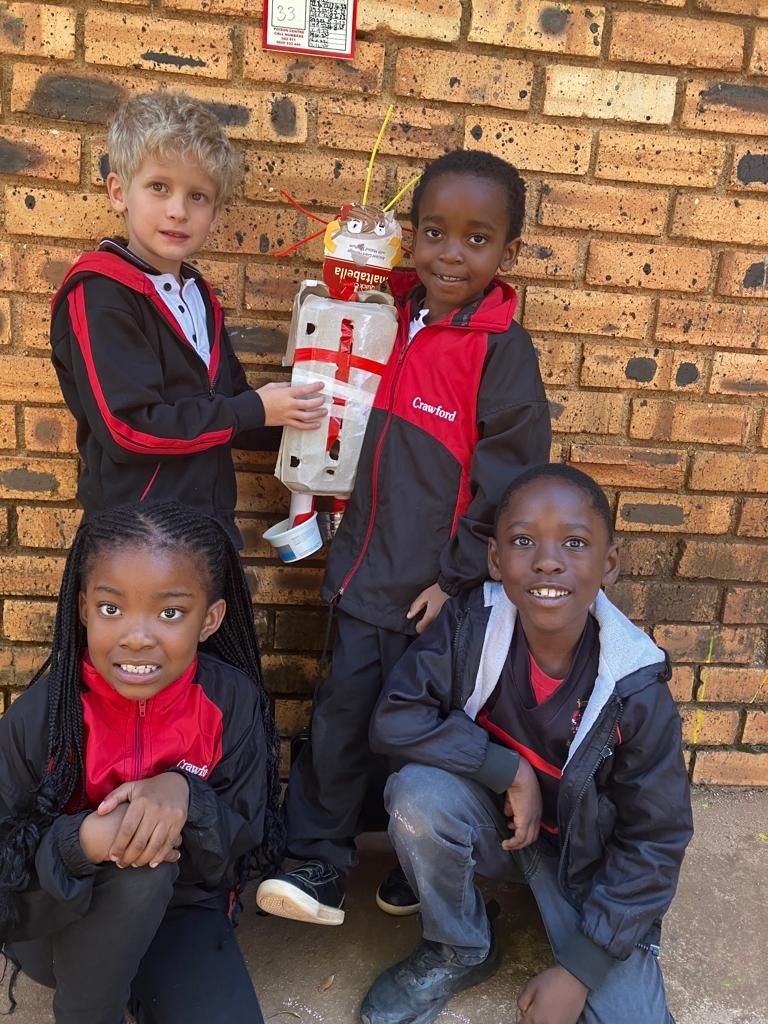 A group of children are posing for a picture in front of a brick wall.