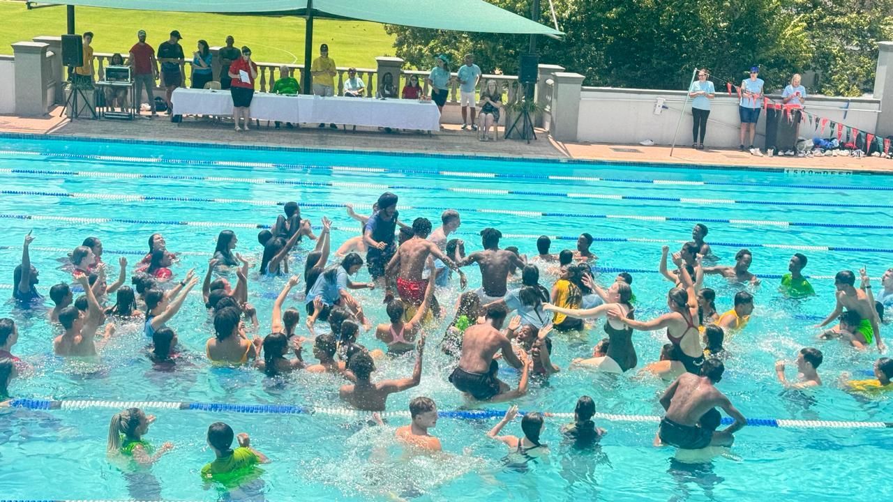 A large group of people are swimming in a swimming pool.