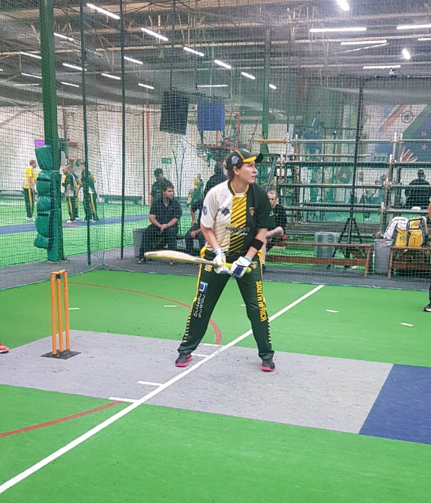 A man is holding a bat on a cricket field.