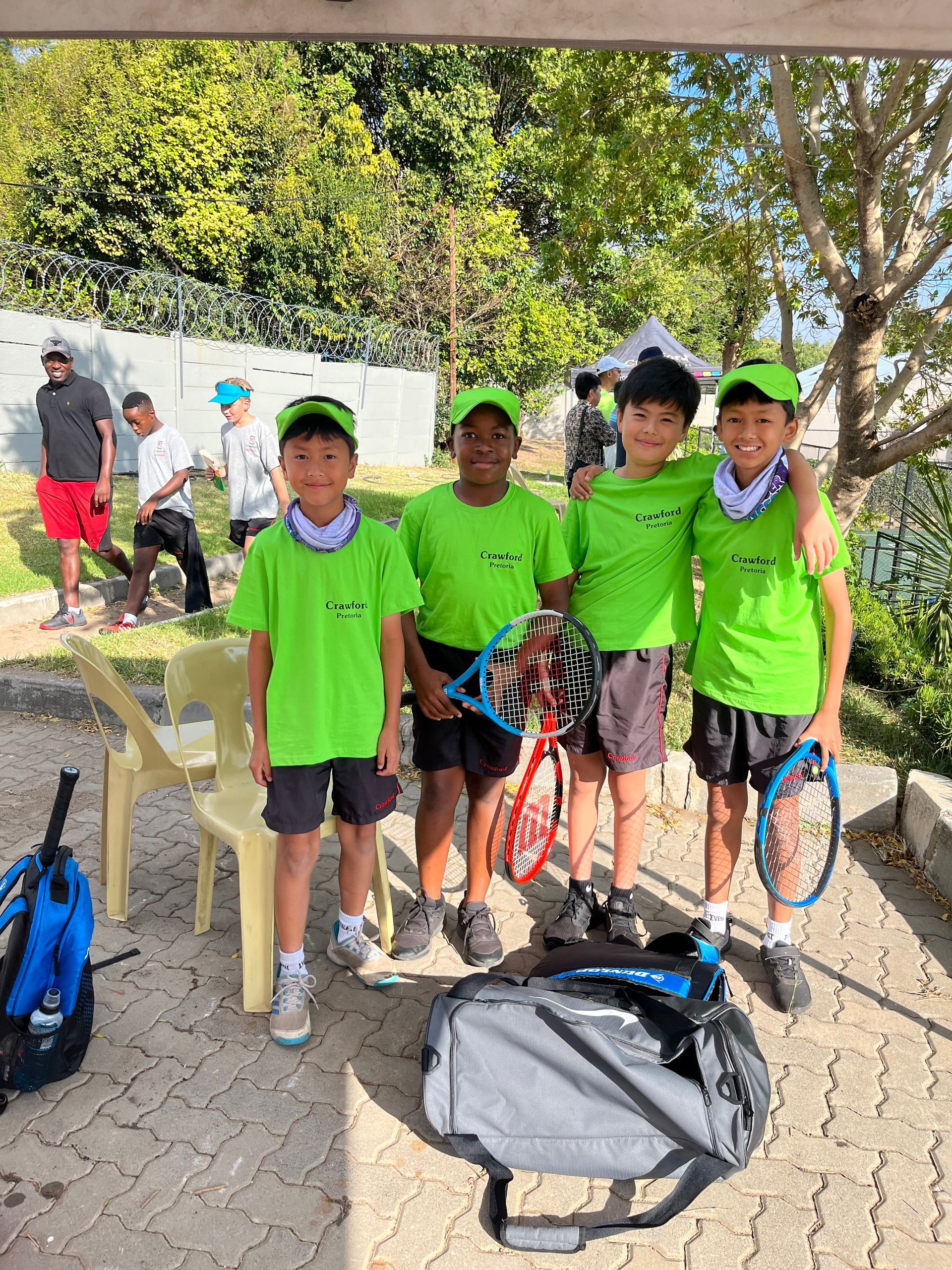 A group of young boys are standing next to each other holding tennis rackets.
