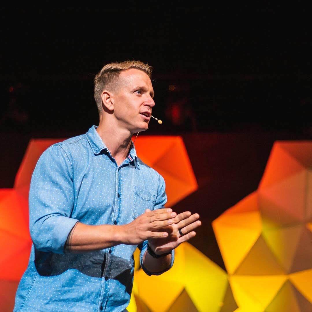 A man in a blue shirt is speaking into a microphone