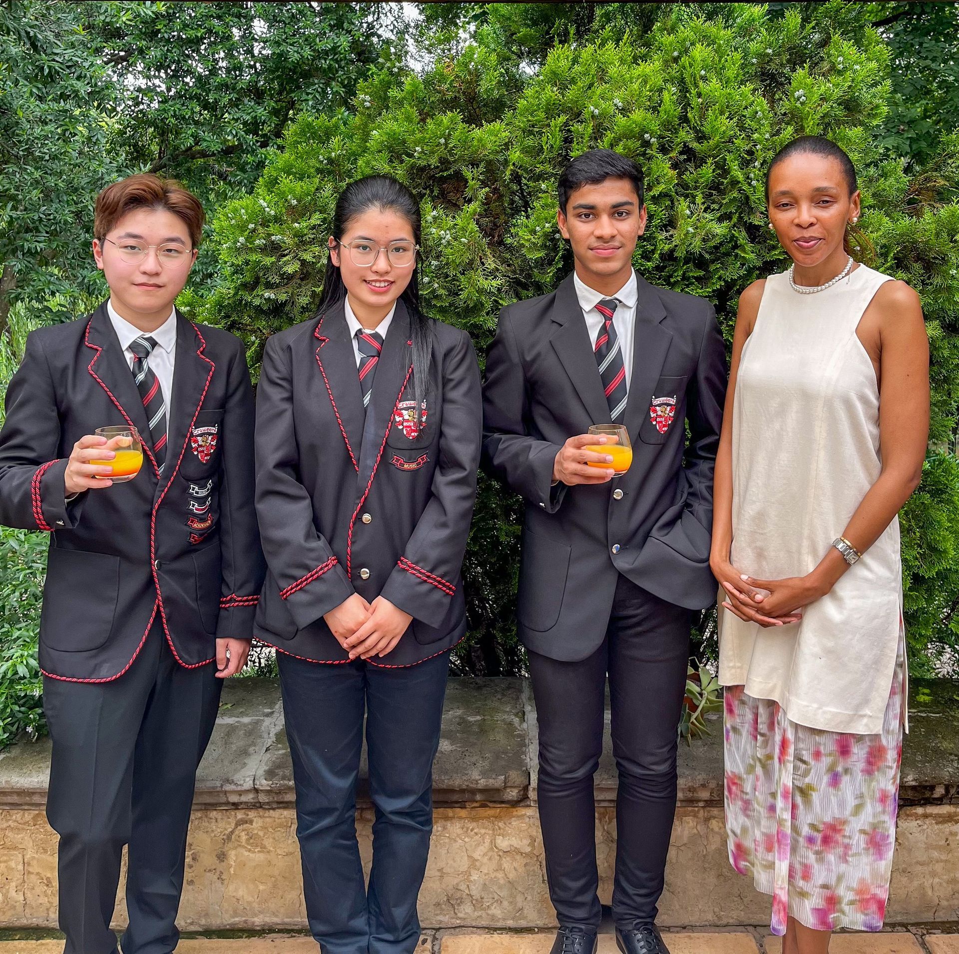 A group of people standing next to each other holding glasses of orange juice