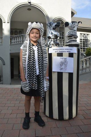 A little girl in a zebra costume is standing next to a statue