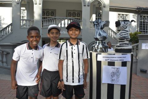 Three young boys are posing for a picture in front of a building
