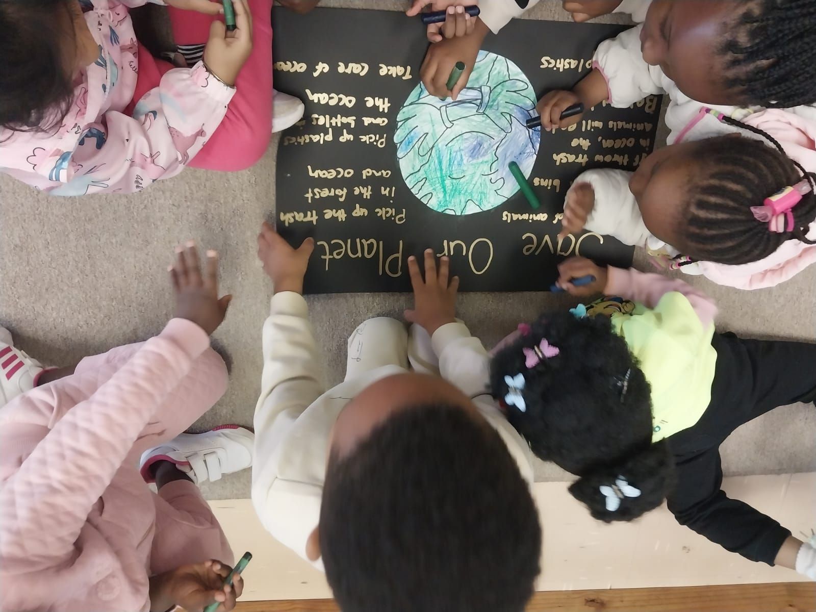 Children drawing on a poster that says 