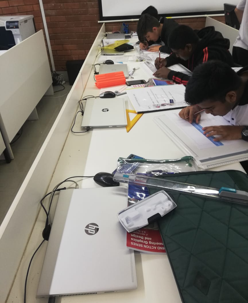 A group of people are sitting at a table with hp laptops