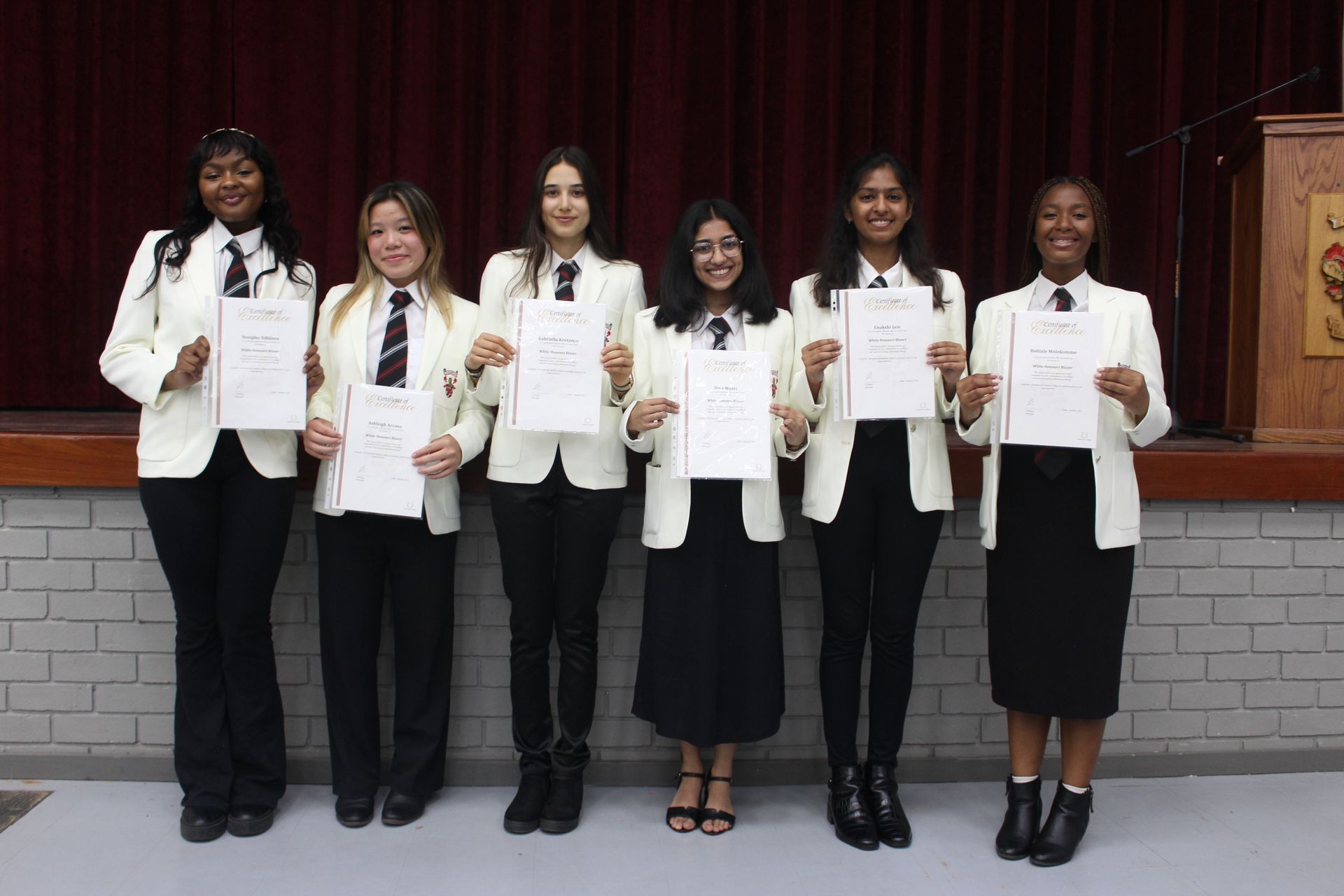 A group of women are standing next to each other holding papers.