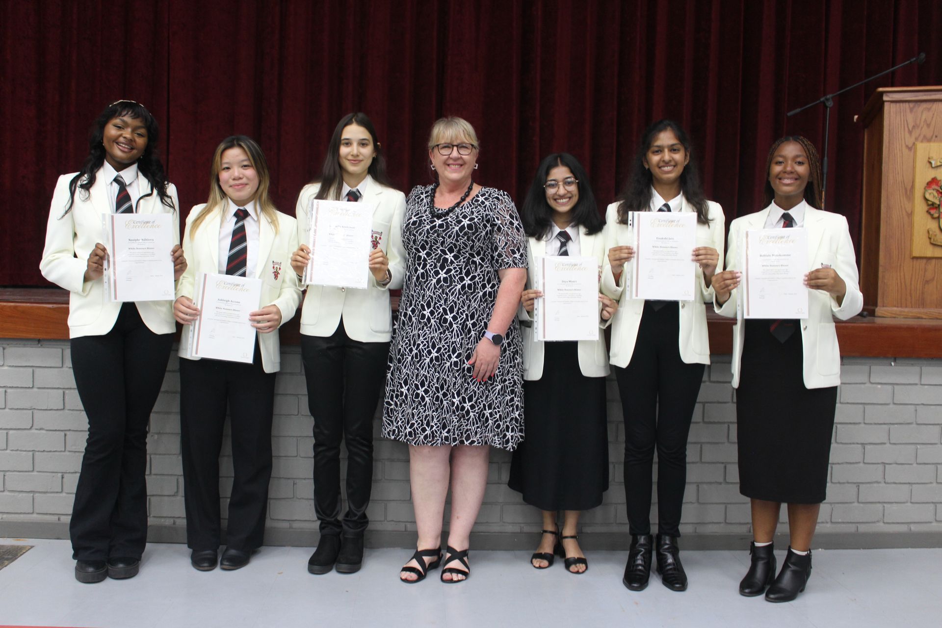 A woman is standing next to a group of girls holding certificates.