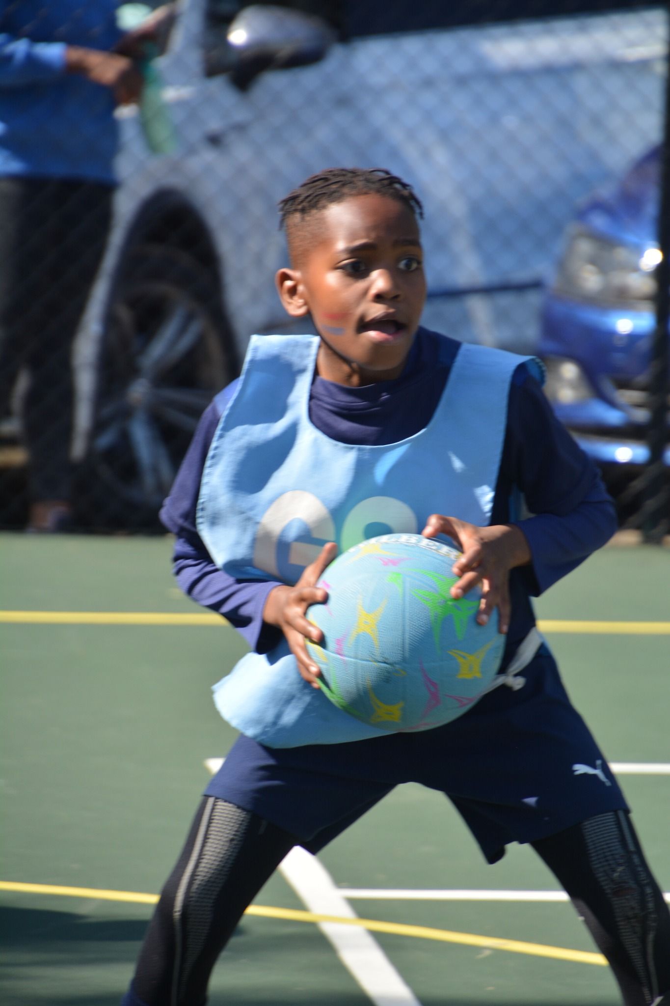 A young boy is holding a ball on a basketball court.