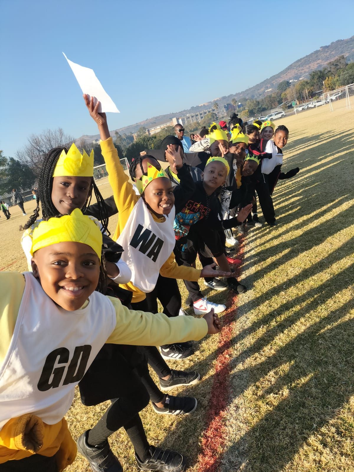 A group of children wearing yellow crowns and shirts that say go