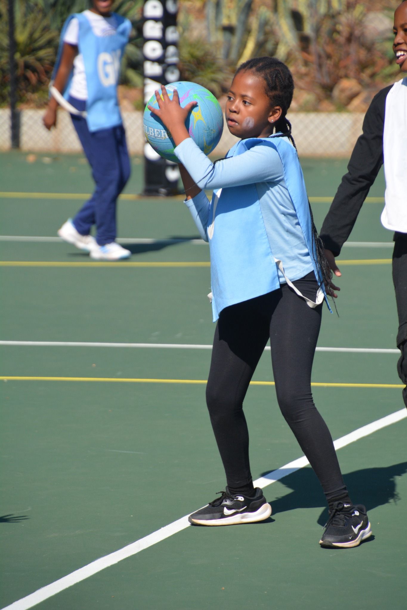 A young girl is holding a ball on a basketball court.
