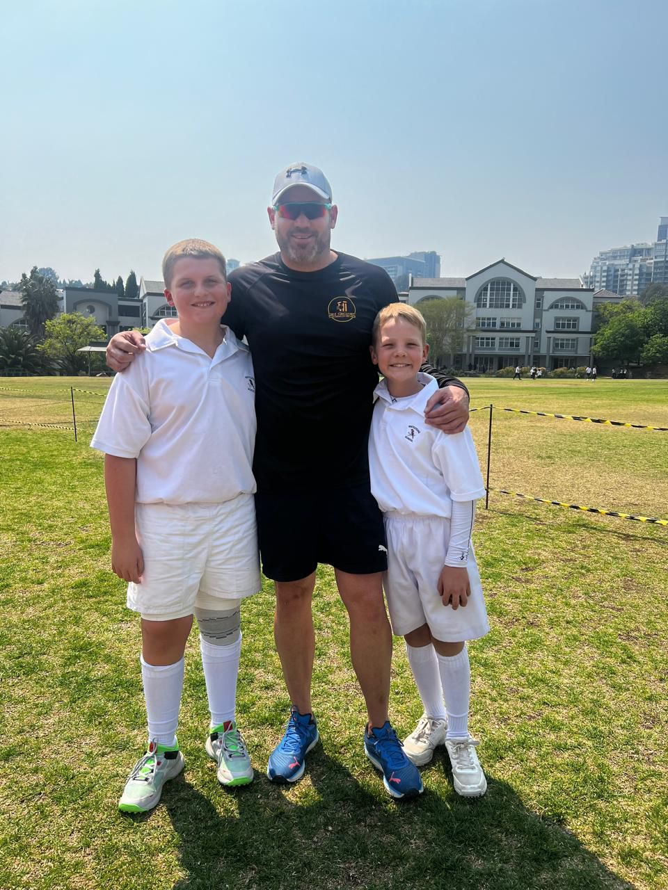 A man and two boys are posing for a picture on a field.