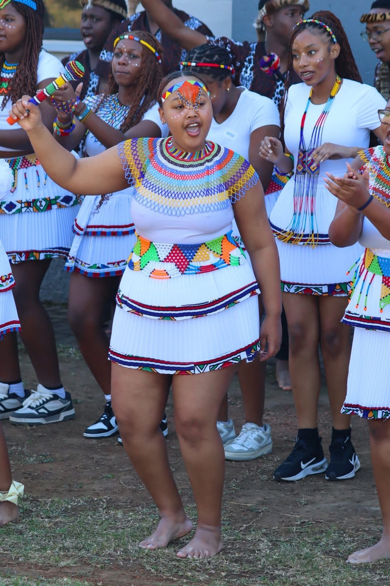 Group of people in traditional clothing dancing and singing outdoors.