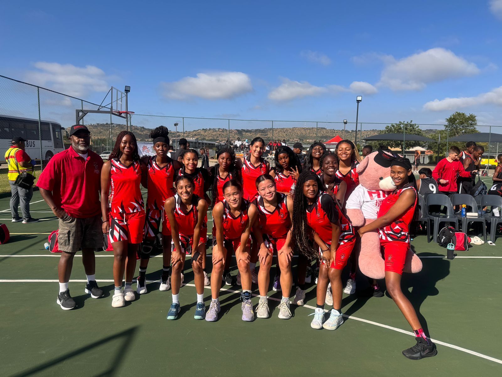 A group of young girls are posing for a picture on a tennis court.