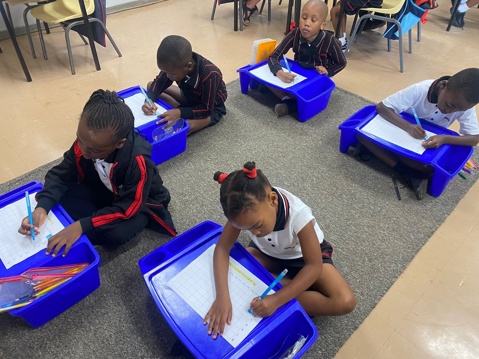 A group of children are sitting on the floor in a classroom.