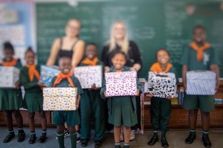 A group of children holding boxes in a classroom