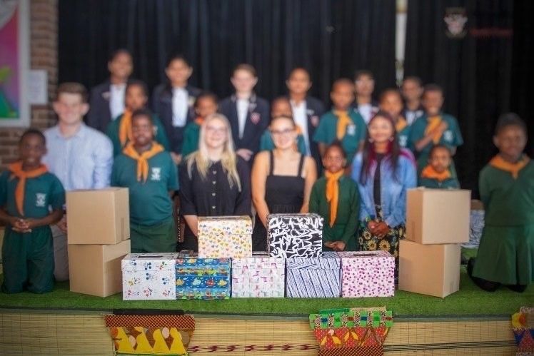 A group of children are standing in front of boxes on a stage.