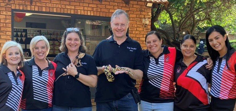 A group of people standing next to each other holding a lizard.