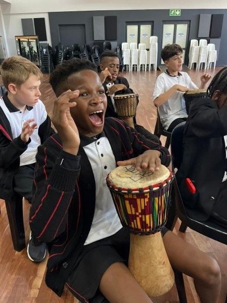 A boy in a tuxedo is playing a drum in a group of children.